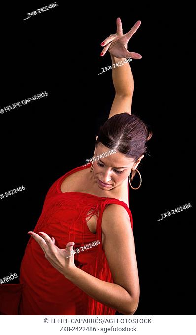 Flamenco dancer backs red dress and hands crossed up on his back on black background