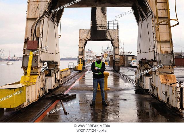 Dock worker standing with arms crossed in shipyard
