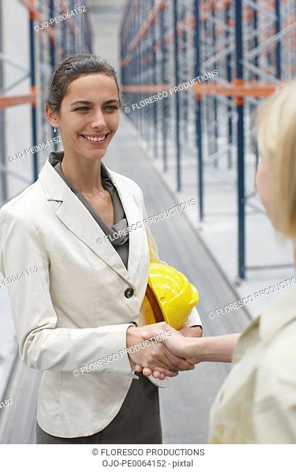 Businesswoman shaking hands in warehouse