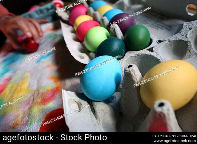 06 April 2023, Bavaria, Kaufbeuren: A woman sorts brightly colored eggs into an egg carton. Photo: Karl-Josef Hildenbrand/dpa