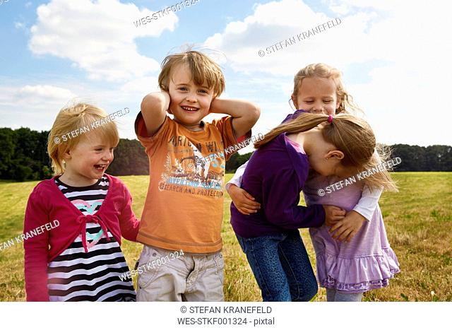 Four little children playing on a meadow