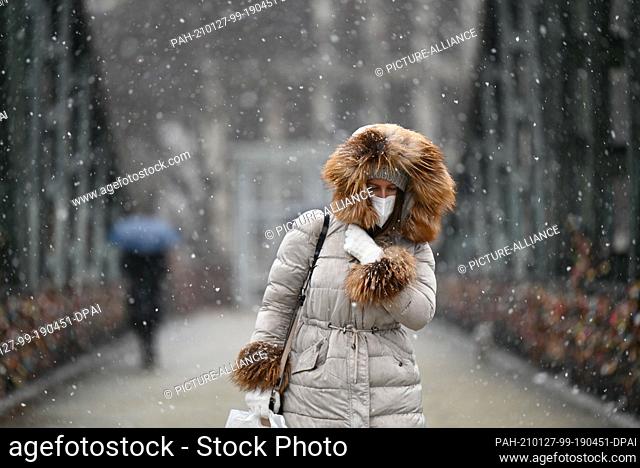 27 January 2021, Hessen, Frankfurt/Main: Protected by winter clothing, Ivana walks across the Iron Bridge in the driving snow. Photo: Arne Dedert/dpa
