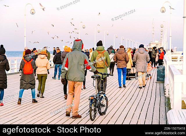 A crowd of people walks on a wooden pier in Sopot, Poland on July 20, 2020 on a sunny winter day near the Baltic Sea. Ative winter vacation near the sea