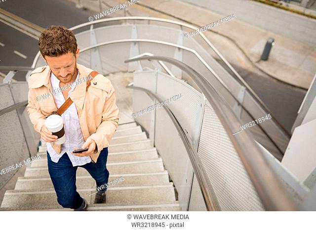 Man walking up stairs while using mobile phone