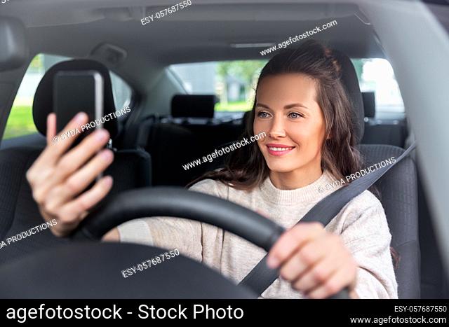 woman or driver driving car and taking selfie