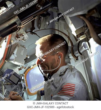 Astronaut Walter Cunningham, Apollo 7 lunar module pilot, writes with space pen as he is photographed performing flight tasks on the ninth day of the Apollo 7...