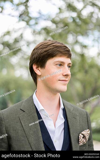 Smiling young groom wearing suit at wedding ceremony