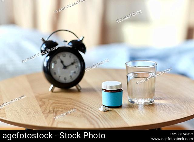alarm clock, sleeping pills and glass of water