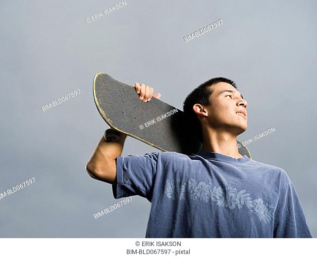 Mixed race teenager standing with skateboard