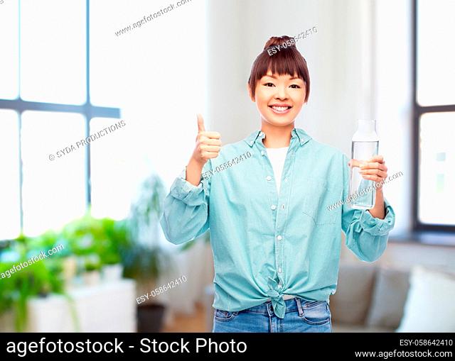 happy asian woman holding glass bottle with water