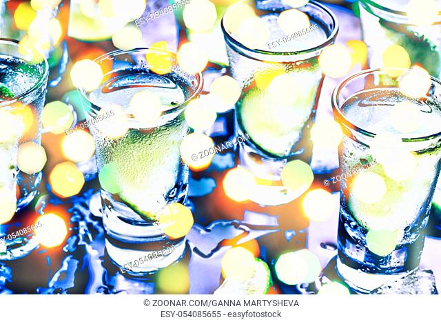 A party in the club. Cocktails on the bar. Alcohol. Vodka, gin, tequila with ice and lime. Alcoholic cocktail cocktail. Selective focus glasses of cold vodka on...