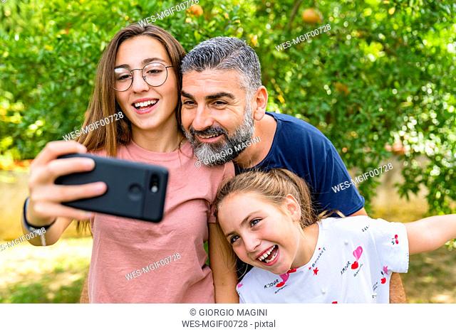 Happy father with two daughters taking selfie in garden