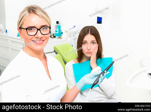 Young dentist woman going to use a drill to solve the young lady#39;s problem connected with dental caries at dentist#39;s office