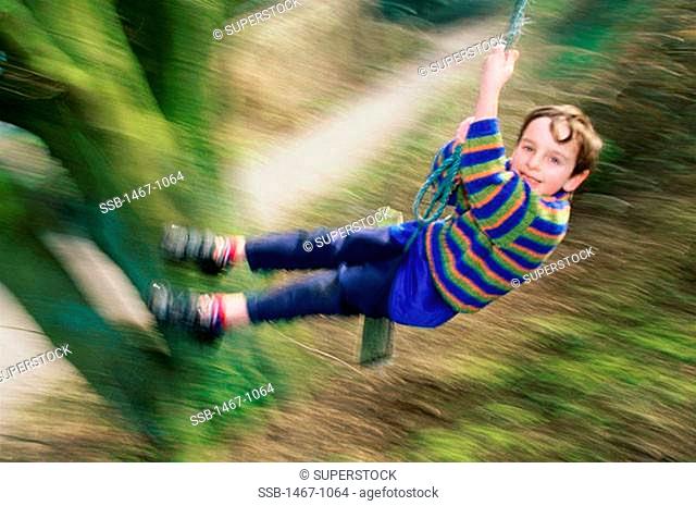 High angle view of a boy swinging on a rope swing