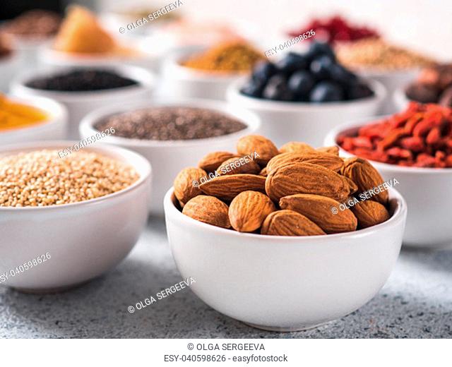 Almond in small white bowl and other superfoods on background. Selective focus. Different superfoods ingredients. Concept and illustration for superfood and...