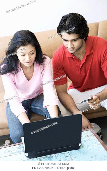 High angle view of a young couple shopping online with a credit card