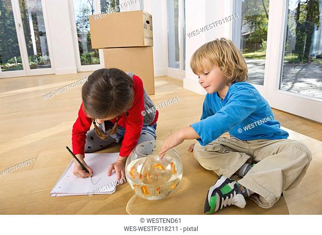 Germany, Bavaria, Grobenzell, Girl drawing and boy playing with goldfish bowl, smiling