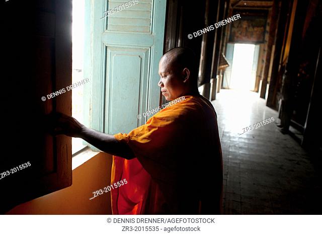 A monk closes a window in a small village temple outside of Phnom Penh, Cambodia