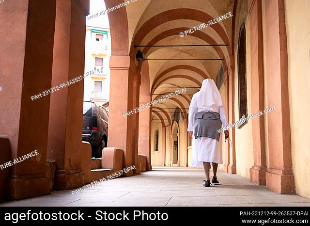 14 October 2023, Italy, Bologna: A nun walks under the arcades of Bologna. Photo: Sebastian Kahnert/dpa. - Bologna/Emilia-Romagna/Italy