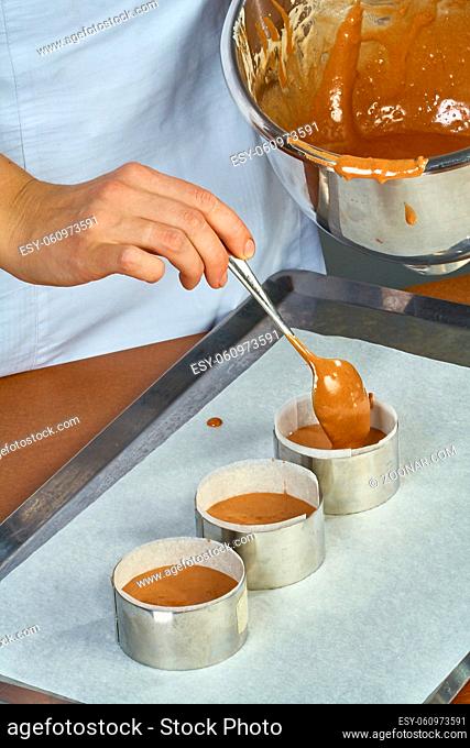 The cook pours the dough into forms for making cupcakes Complete collection of recipes