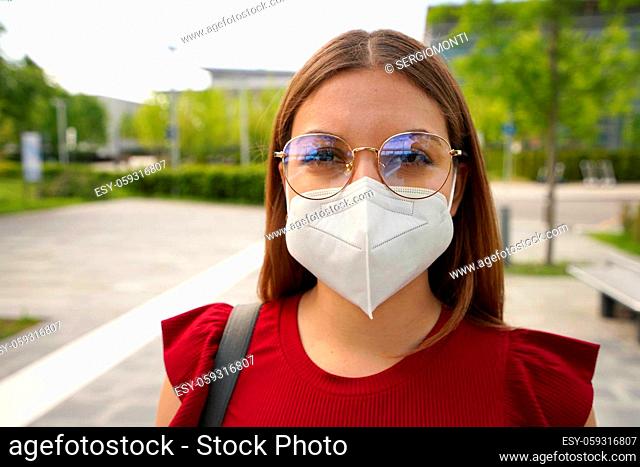Close up portrait of young woman wearing glasses and protective mask KN95 FFP2 outside