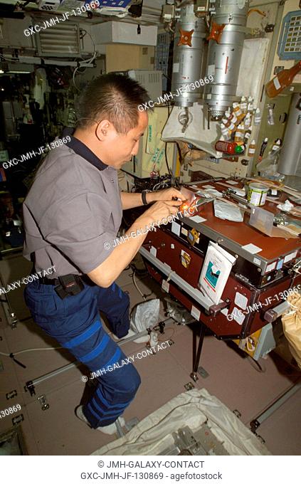 Astronaut Edward T. Lu, Expedition 7 NASA ISS science officer and flight engineer, prepares to eat a meal in the Zvezda Service Module on the International...