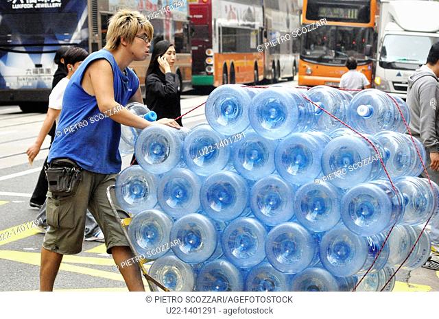 Hong Kong: a delivery boy pushing a cart with many water tanks in Central