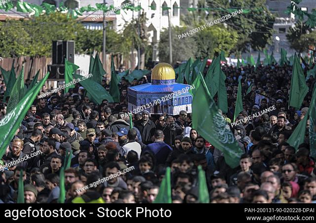 31 January 2020, Palestinian Territories, Jabalia: Palestinians wave Hamas movement flags and hold a replica of Jerusalem's Dome of the Rock mosque during a...