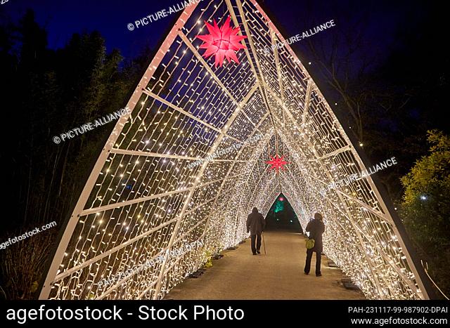 17 November 2023, Hamburg: Two visitors take a photo of themselves with their cell phones under a light installation in the ""Christmas Garden"" in the Loki...
