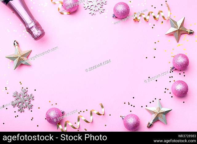 Flat lay composition of Champagne bottle golden and pink Christmas decorations on trendy pink background copy space