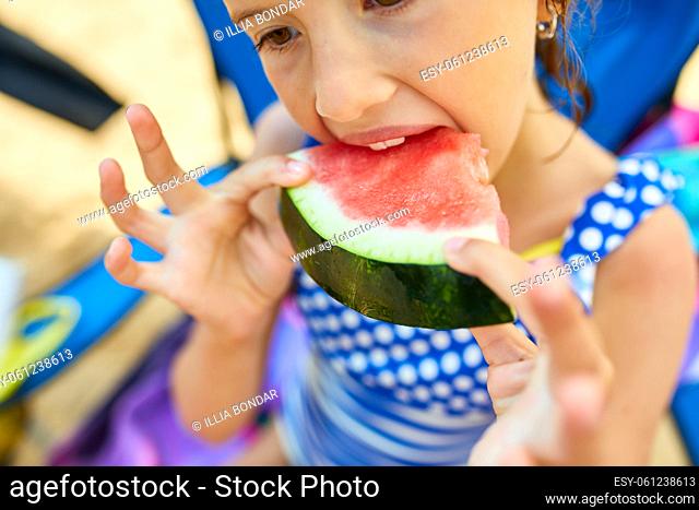 Little girl holding slice of watermelon on the beach and eating, Summer lifestyle Happiness, joy, holiday, beach, summertime concept