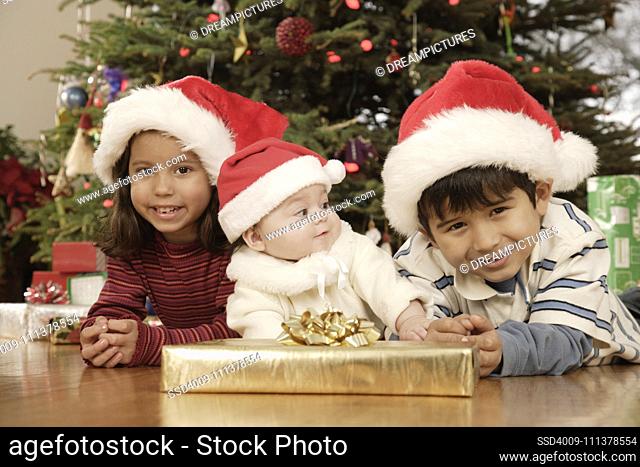 Hispanic siblings wearing Santa Claus hats