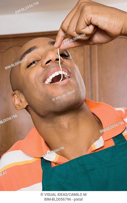 African man eating piece of spaghetti