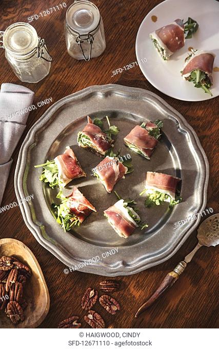 Prosciutto, arugula and goat cheese rollups on silver platter