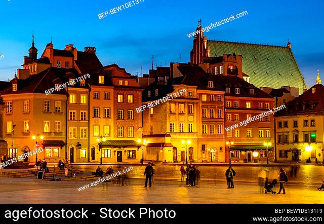 Warsaw, Poland - April 28, 2021: Evening panorama of Castle Square with colorful tenement houses and silhouette of St. Jogn Cathedral in Starowka Old Town...