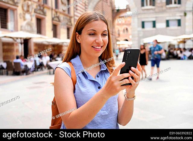 Young woman in blue shirt using telephone for video calling. Girl takes self portrait with smartphone in Verona, Italy