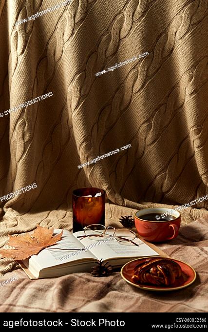 book, cinnamon bun, coffee and candle in autumn