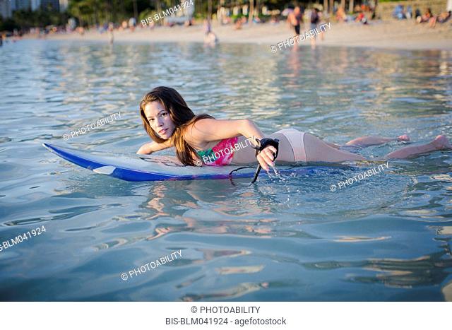 Mixed race amputee swimming with surfboard