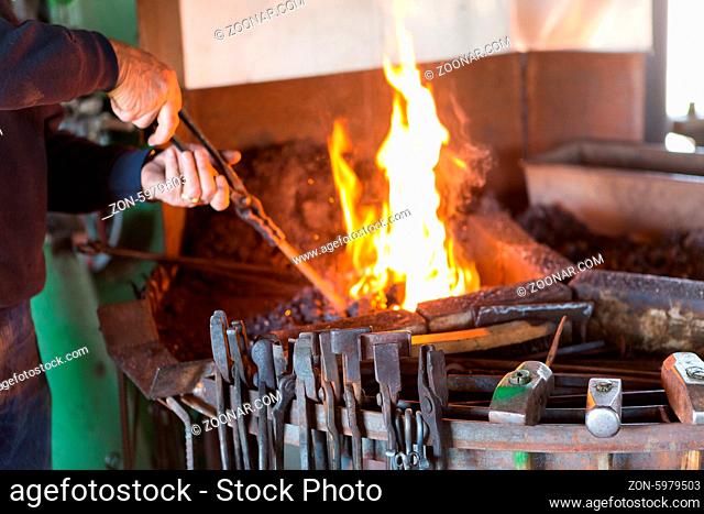 A blacksmith working at an old iron forge