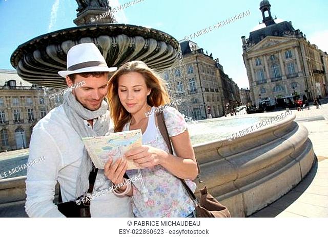 Couple standing by a fountain in Bordeaux with map