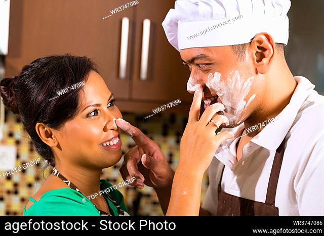 Asian couple in kitchen teasing each other while baking