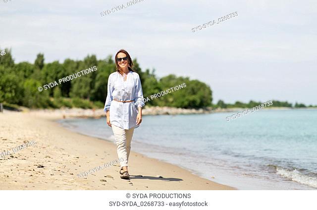 happy smiling woman walking along summer beach