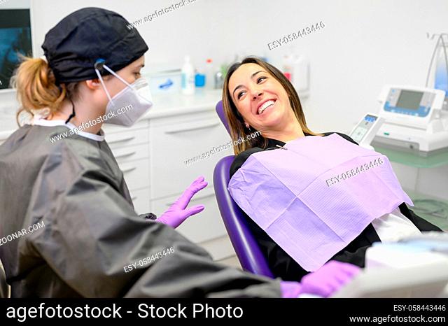 Young female patient visiting dentist office.Beautiful woman sitting at dental chair with open mouth during oral checkup while doctor working at teeth