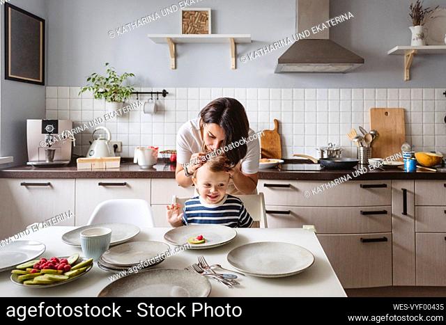 Mother with playful son in kitchen at home