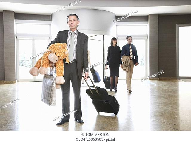 Businessman in lobby with suitcase and stuffed animal