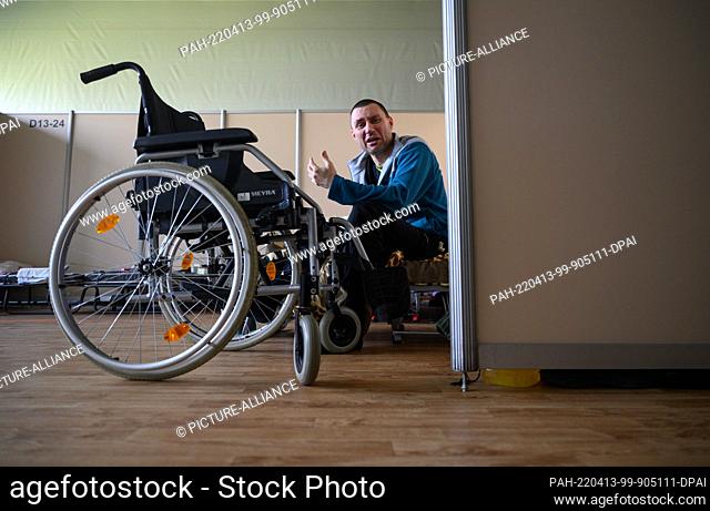 13 April 2022, Saxony, Dresden: Viktor, who fled Bela Tserkva, some 80 kilometers southwest of Kiev, is sitting on a bed next to his wheelchair in the gymnasium...