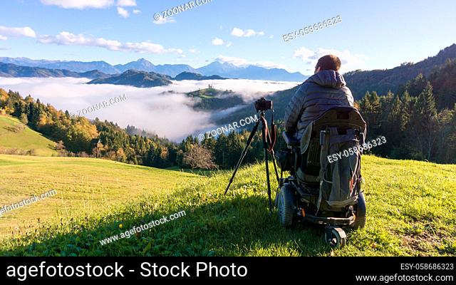 man on wheelchair taking photos of beautiful landscape