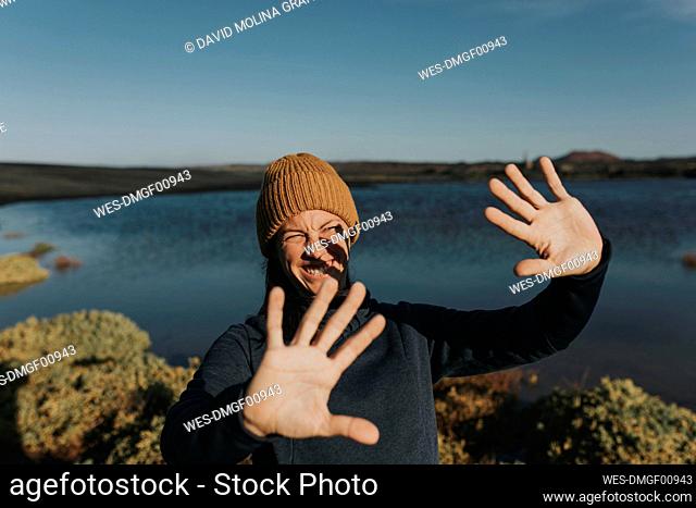 Smiling woman shielding eyes from sunlight at lake