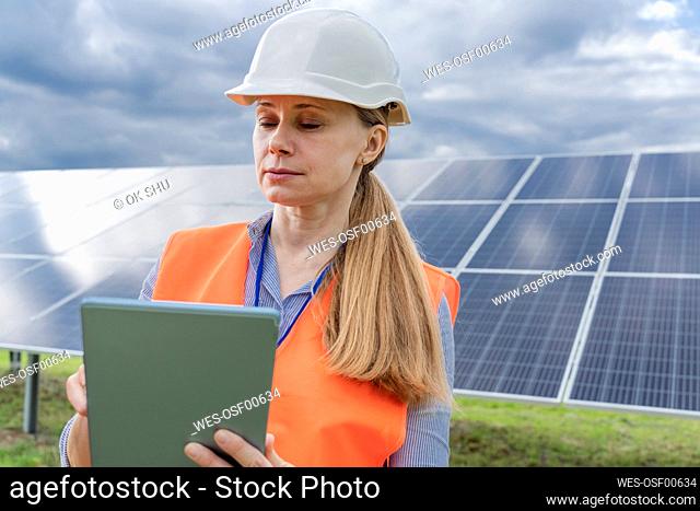 Engineer working on tablet PC in front of solar panels
