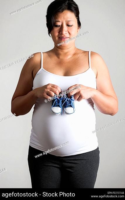 Pregnant woman holding baby shoes